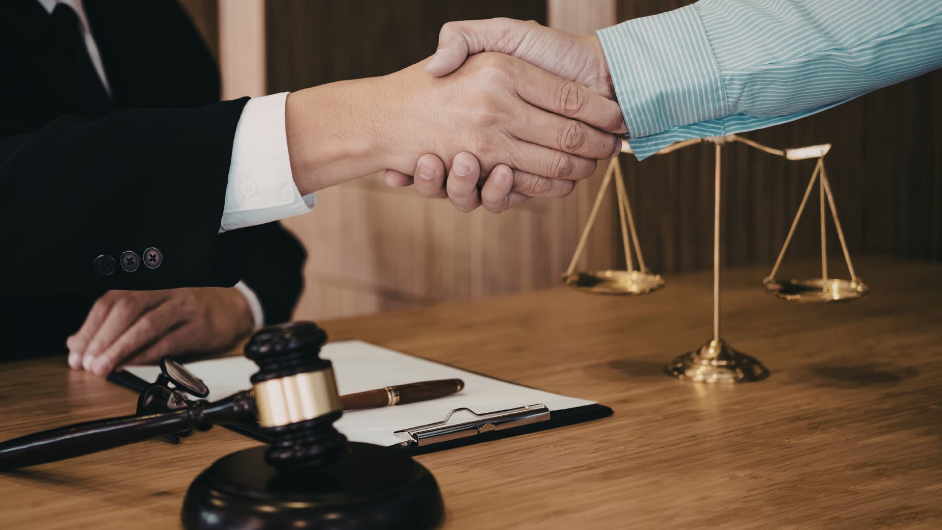 Close-up of a sharp wooden gavel on a blurred desk with a judge background