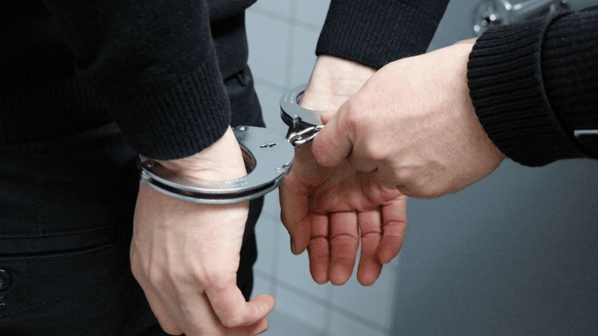 Handcuffs on a suspected criminal in black clothing