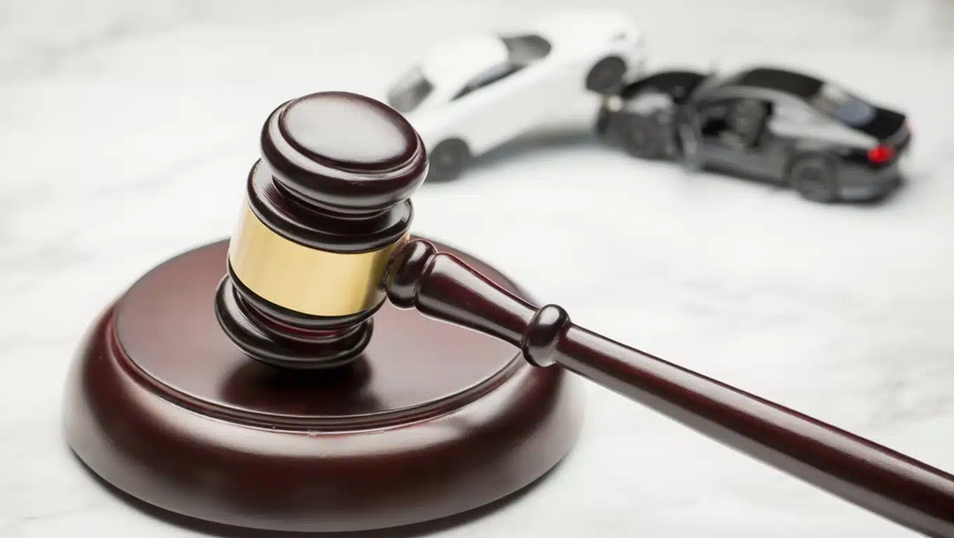 Judge gavel on desk with blurred car crash scene in background representing auto accident lawsuit