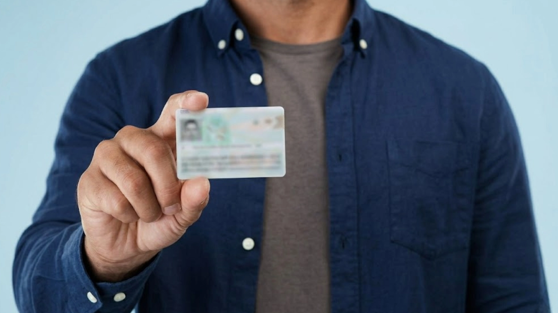 Man holding a green card in hand, showing the front side for identity and immigration document verification purposes
