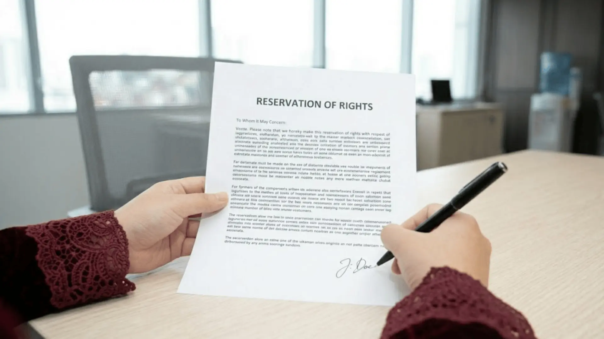 POV shot of a person signing a _RESERVATION OF RIGHTS_ letter with a black pen on a wooden office desk