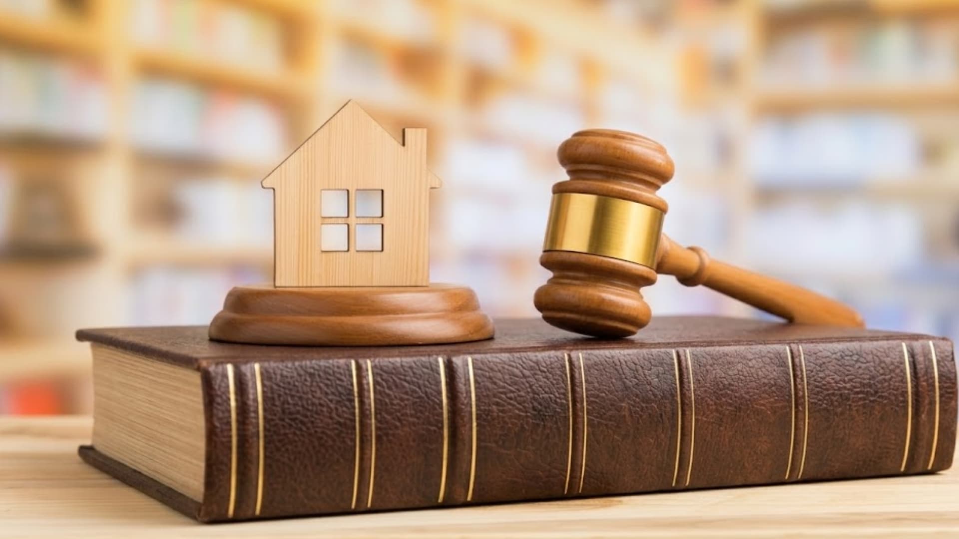 Real estate law concept with house model and gavel on legal book in office setting
