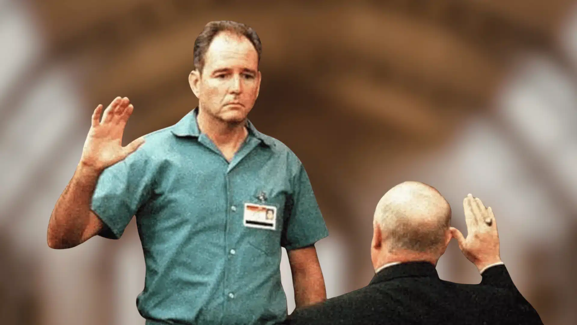 Man raises hand while taking oath in courtroom with official standing in front, blurred courtroom background