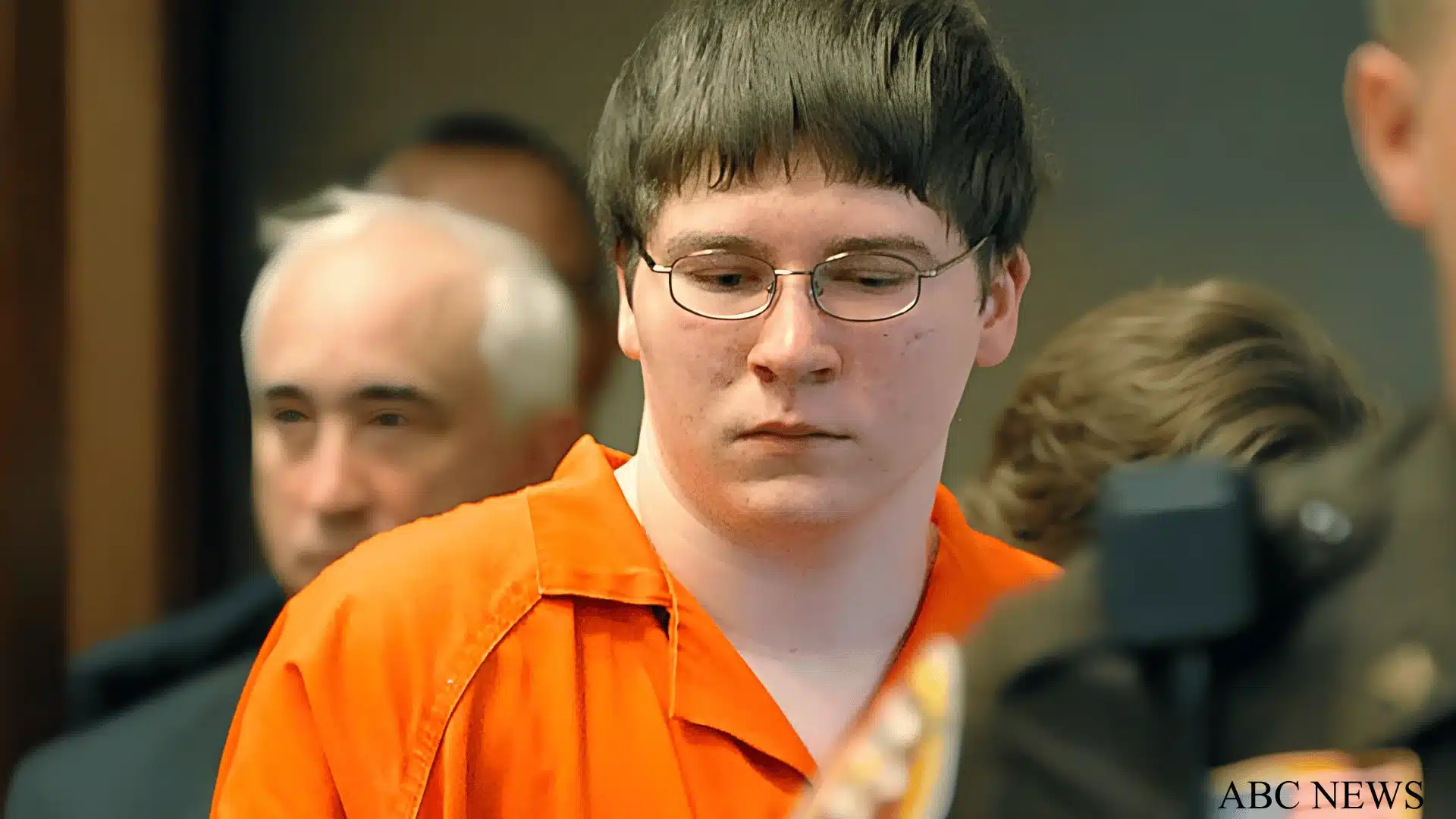 Brendan Dassey in orange prison uniform during courtroom appearance with officers in background