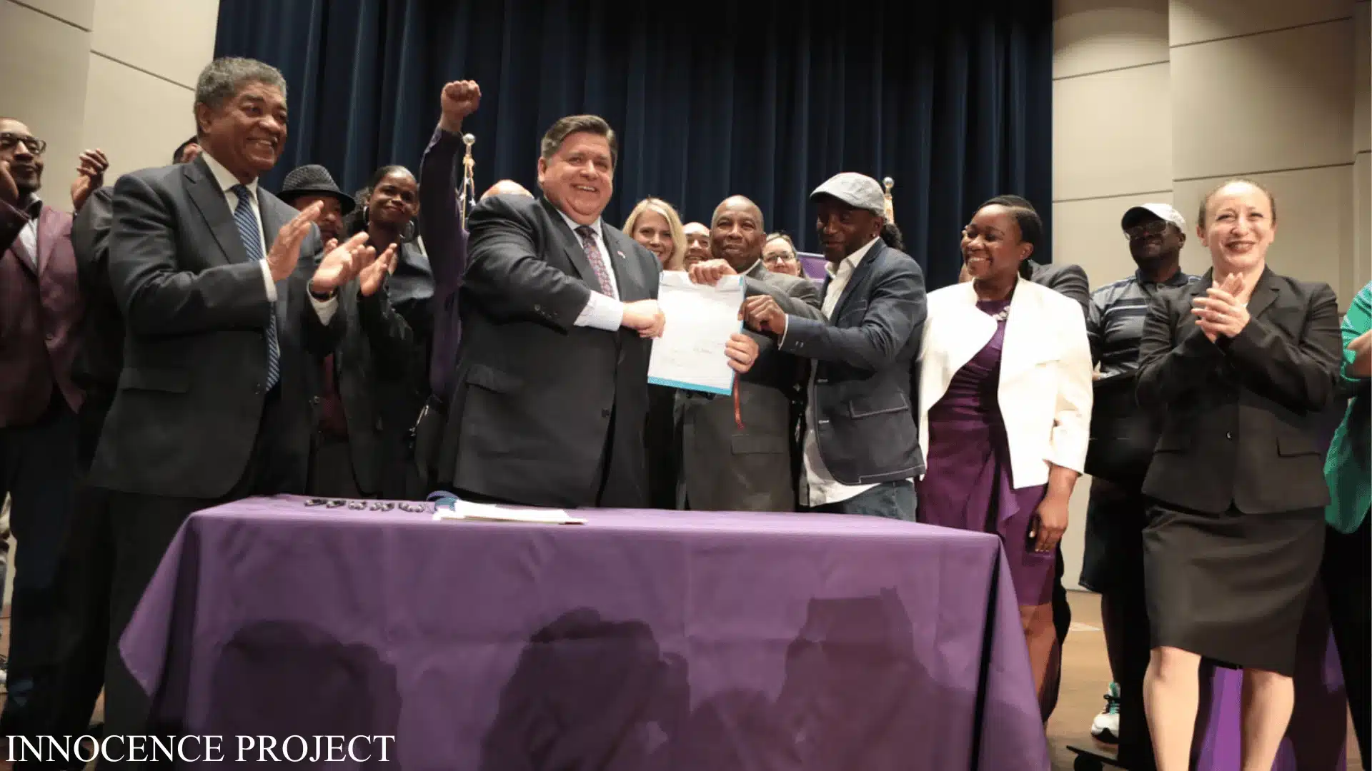 Illinois governor signs clemency document as Innocence Project supporters applaud on stage