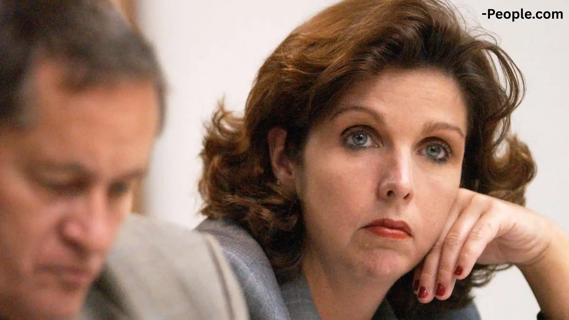 Lynn Turner sitting in court, looking serious, with her attorney blurred in the background