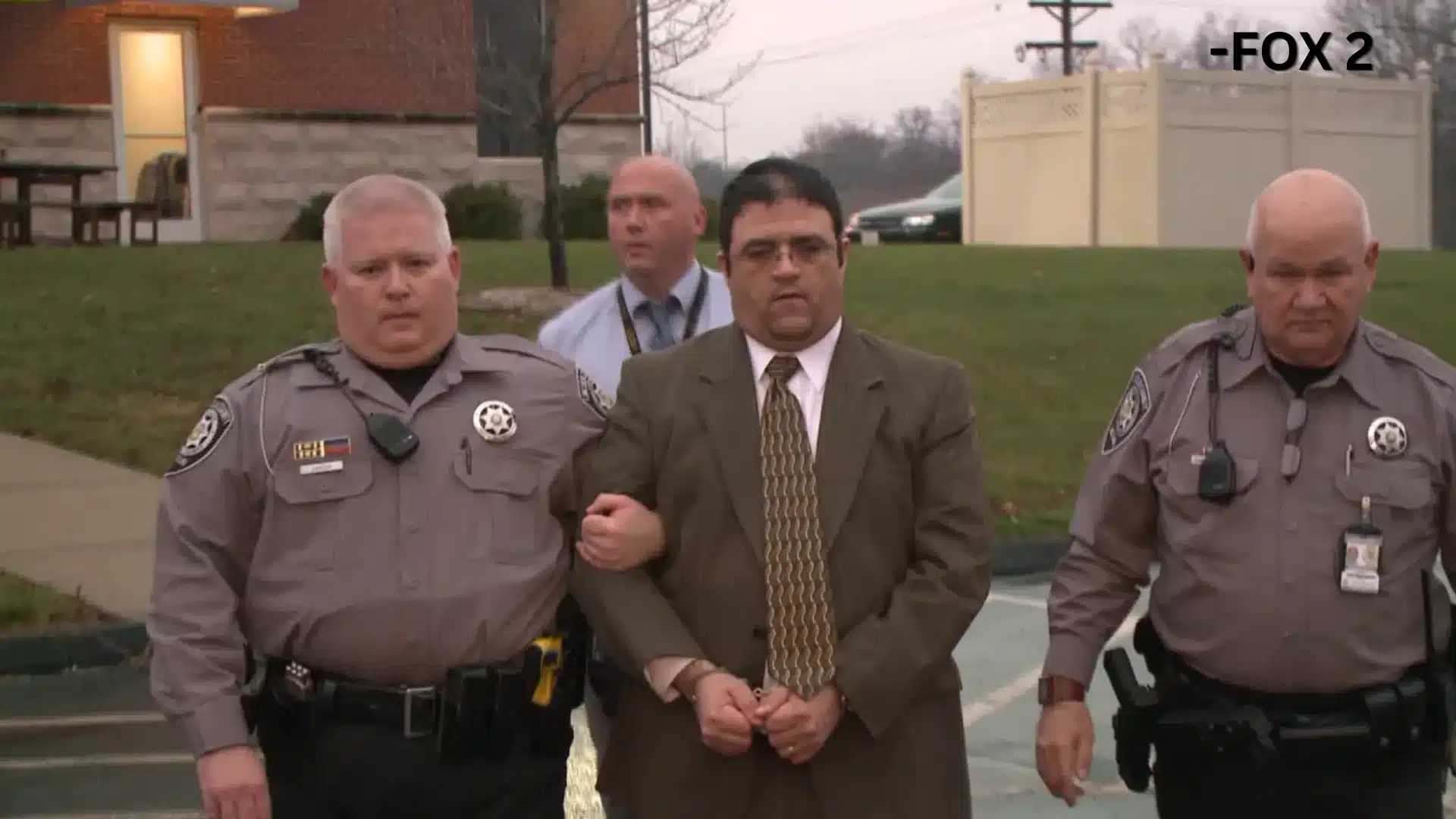 Russell Faria in handcuffs escorted by officers during a criminal case investigation