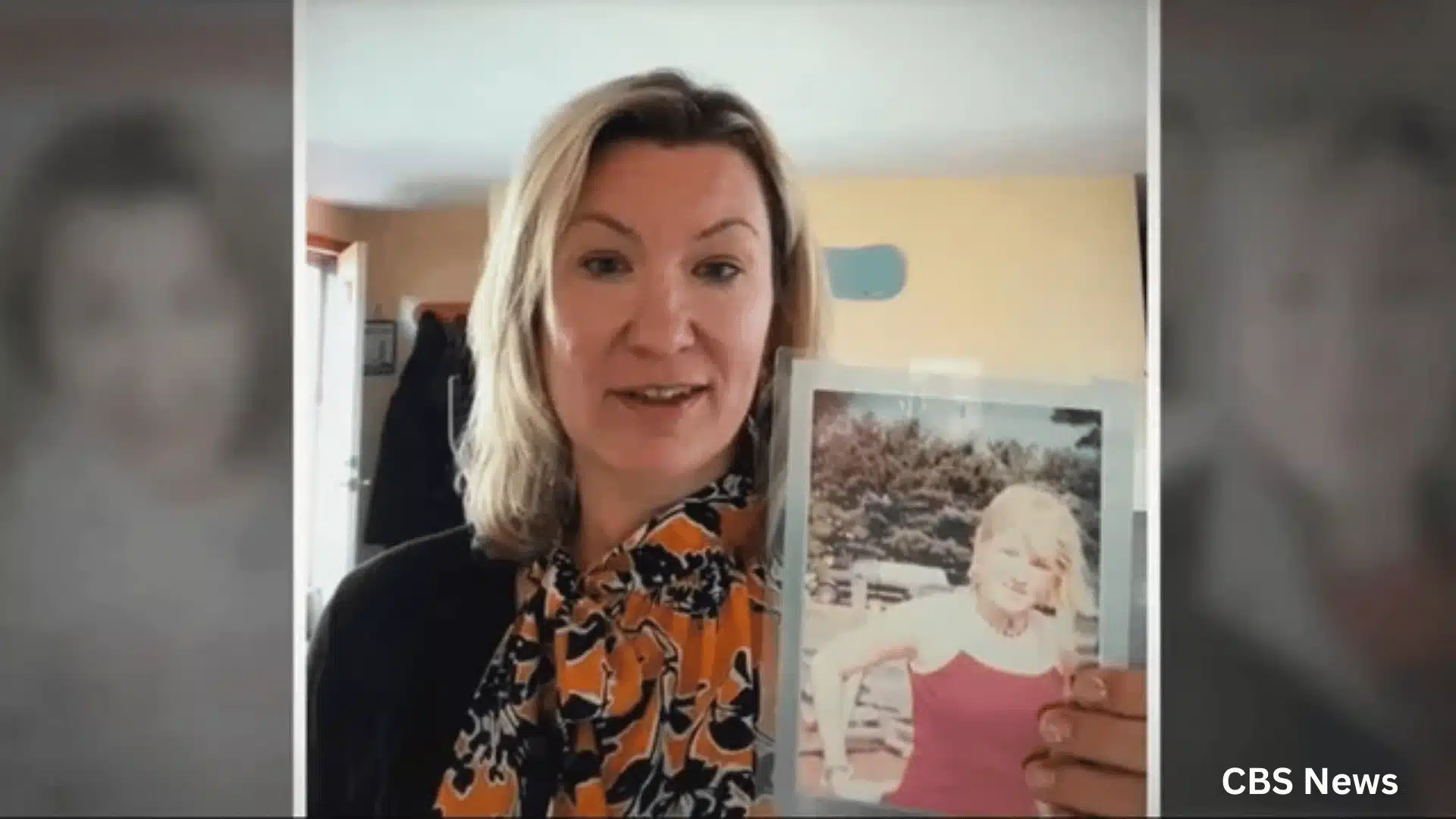 Woman indoors holding a printed photo of a young girl in a red top
