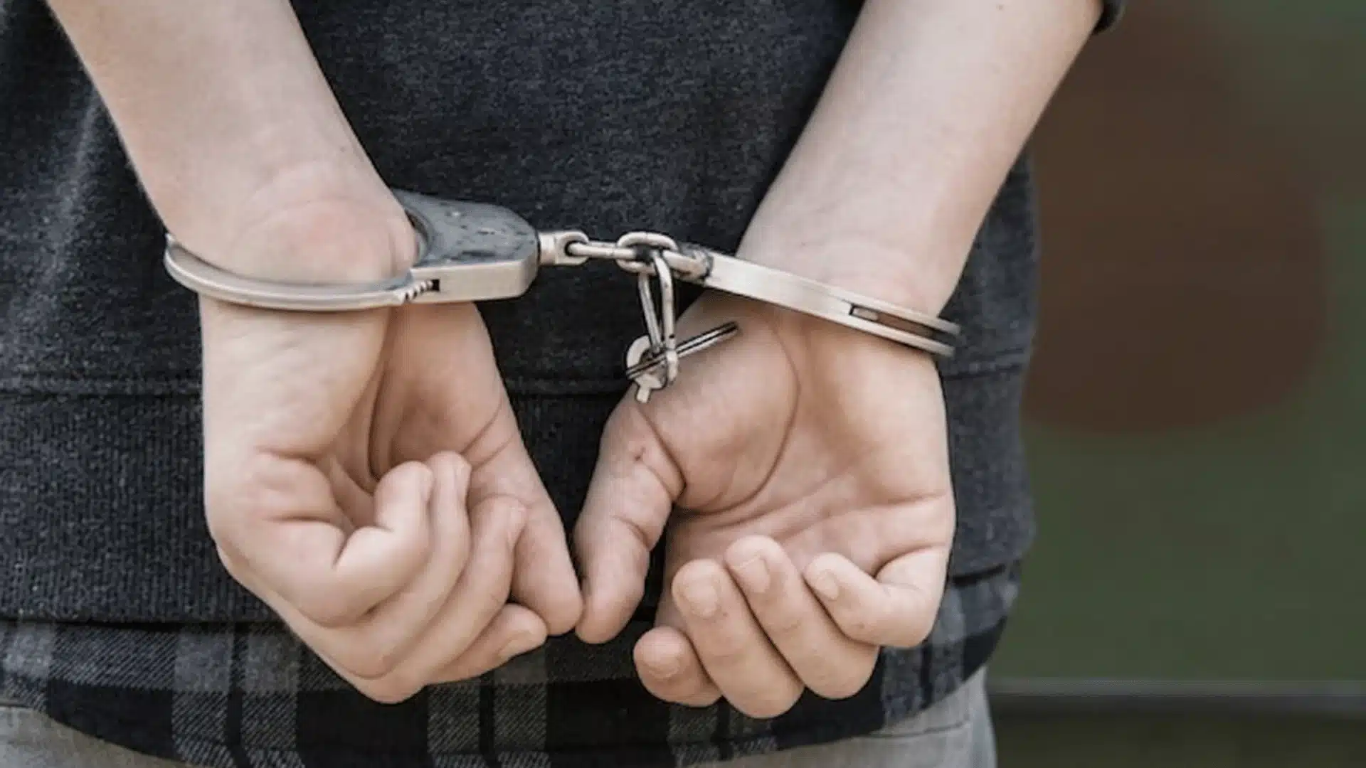 Handcuffed person with hands behind their back, representing arrest after a criminal accusation