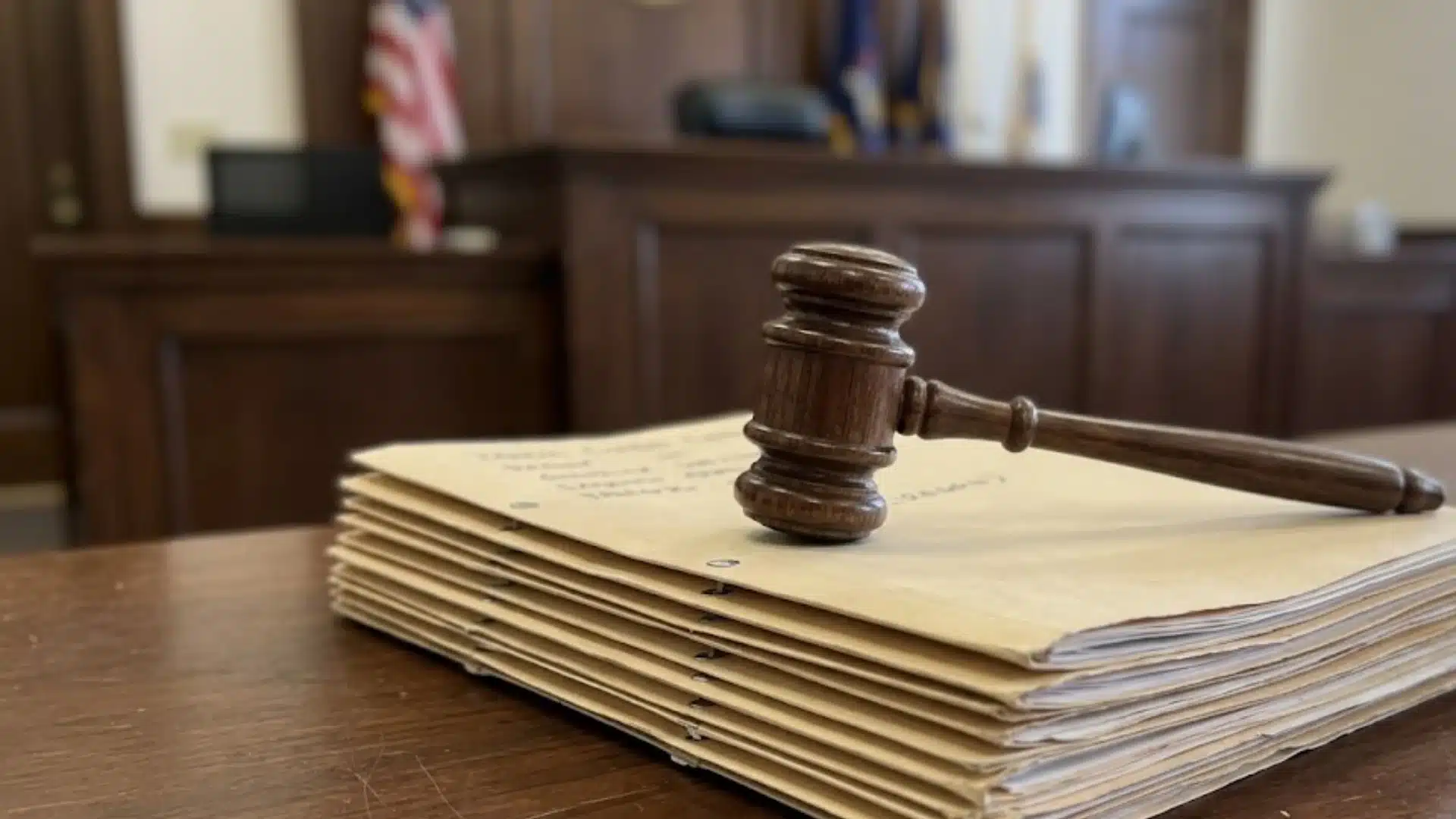 Wooden gavel resting beside a stack of case files and law books on a courtroom desk