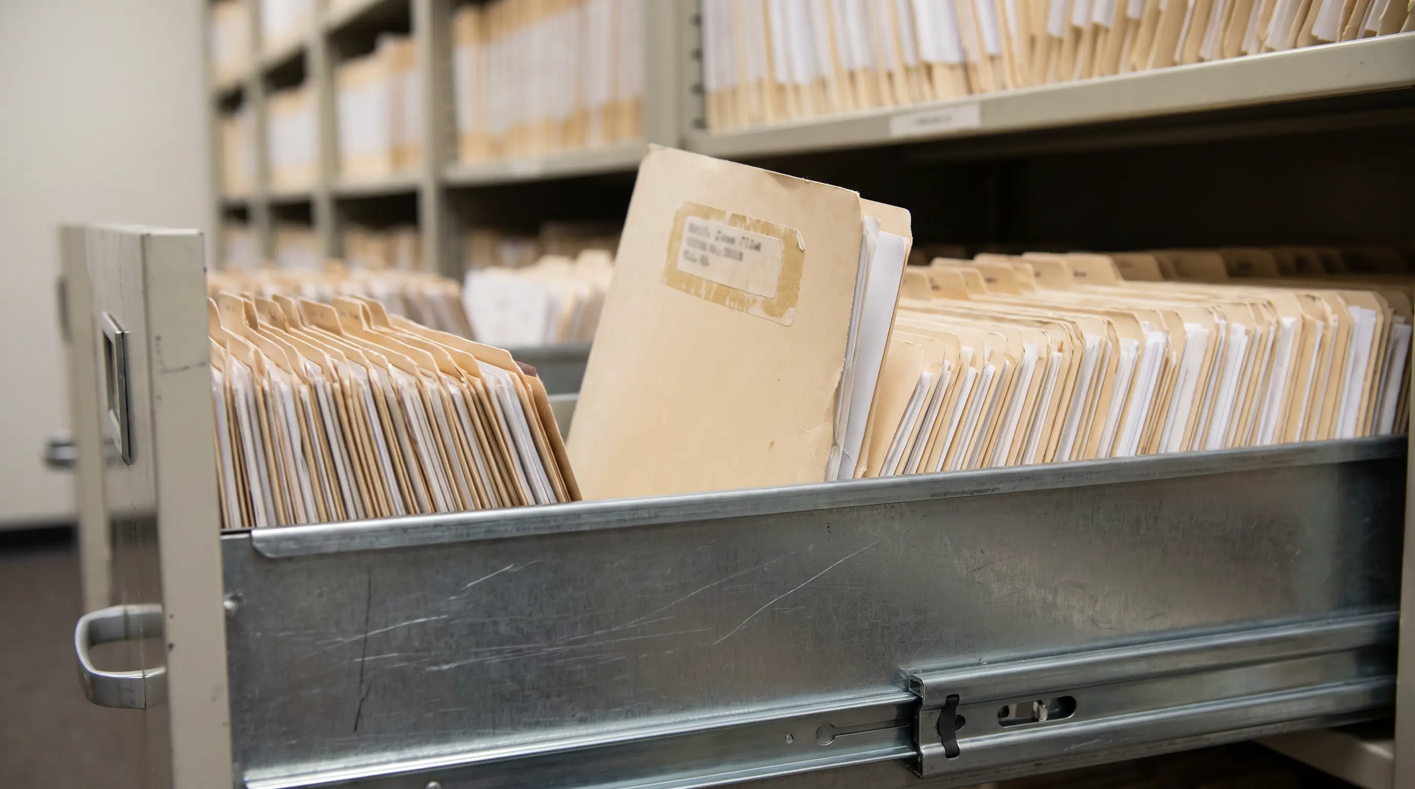 Legal case file removed from an open drawer in an organized courthouse records room.