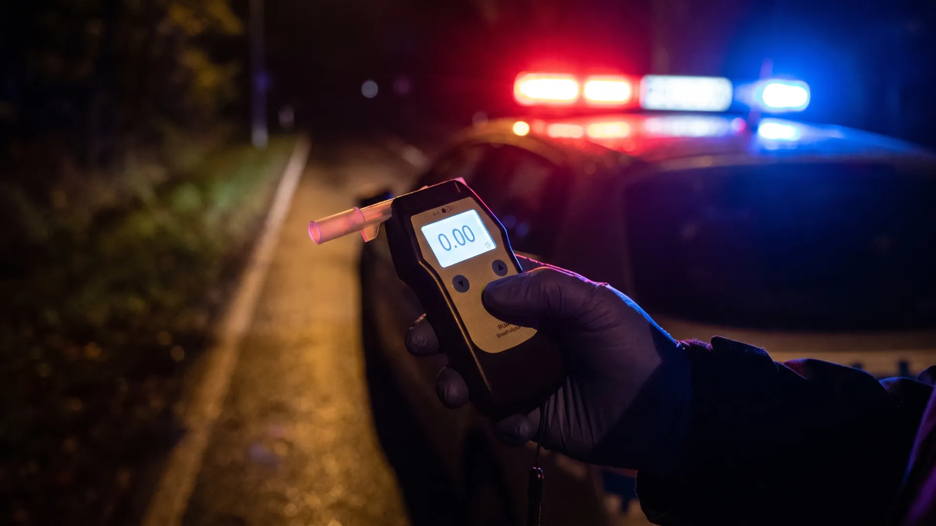 Police officer holding a breathalyzer during a nighttime DUI traffic stop
